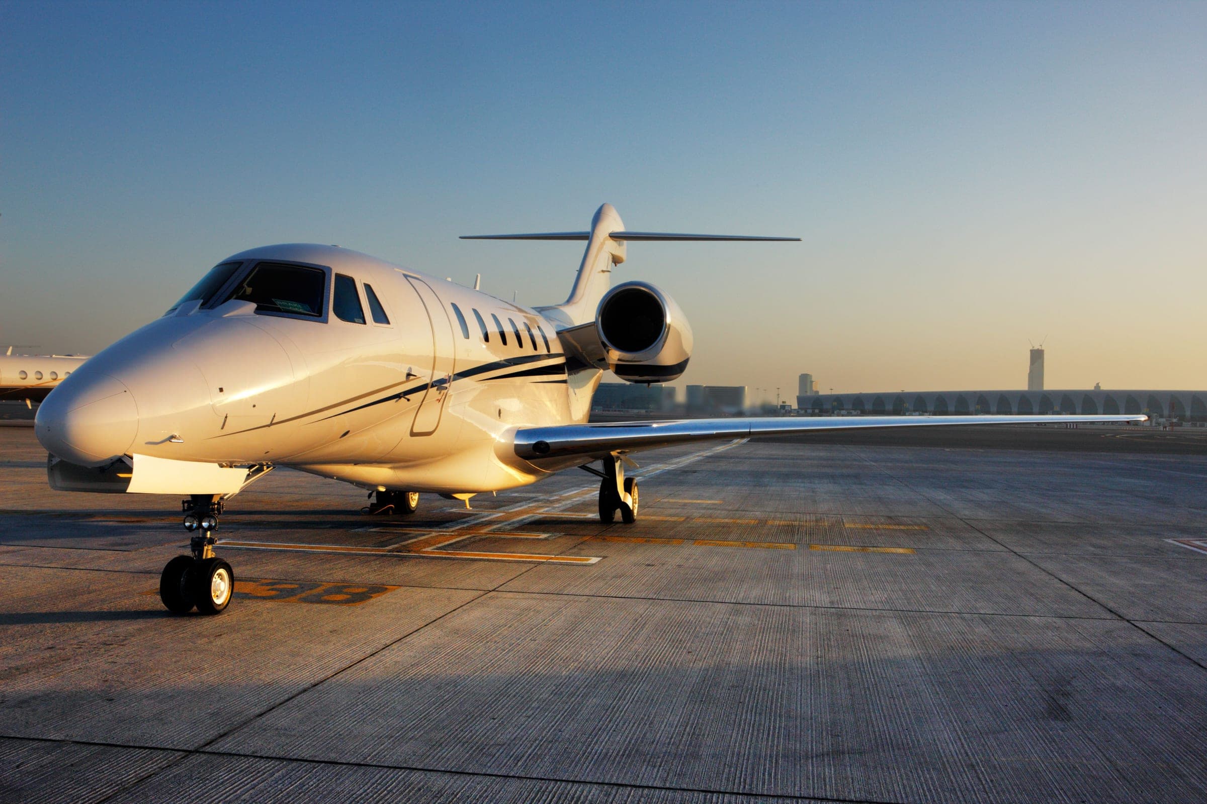 A business jet on the ramp at golden hour, the nose catching the light